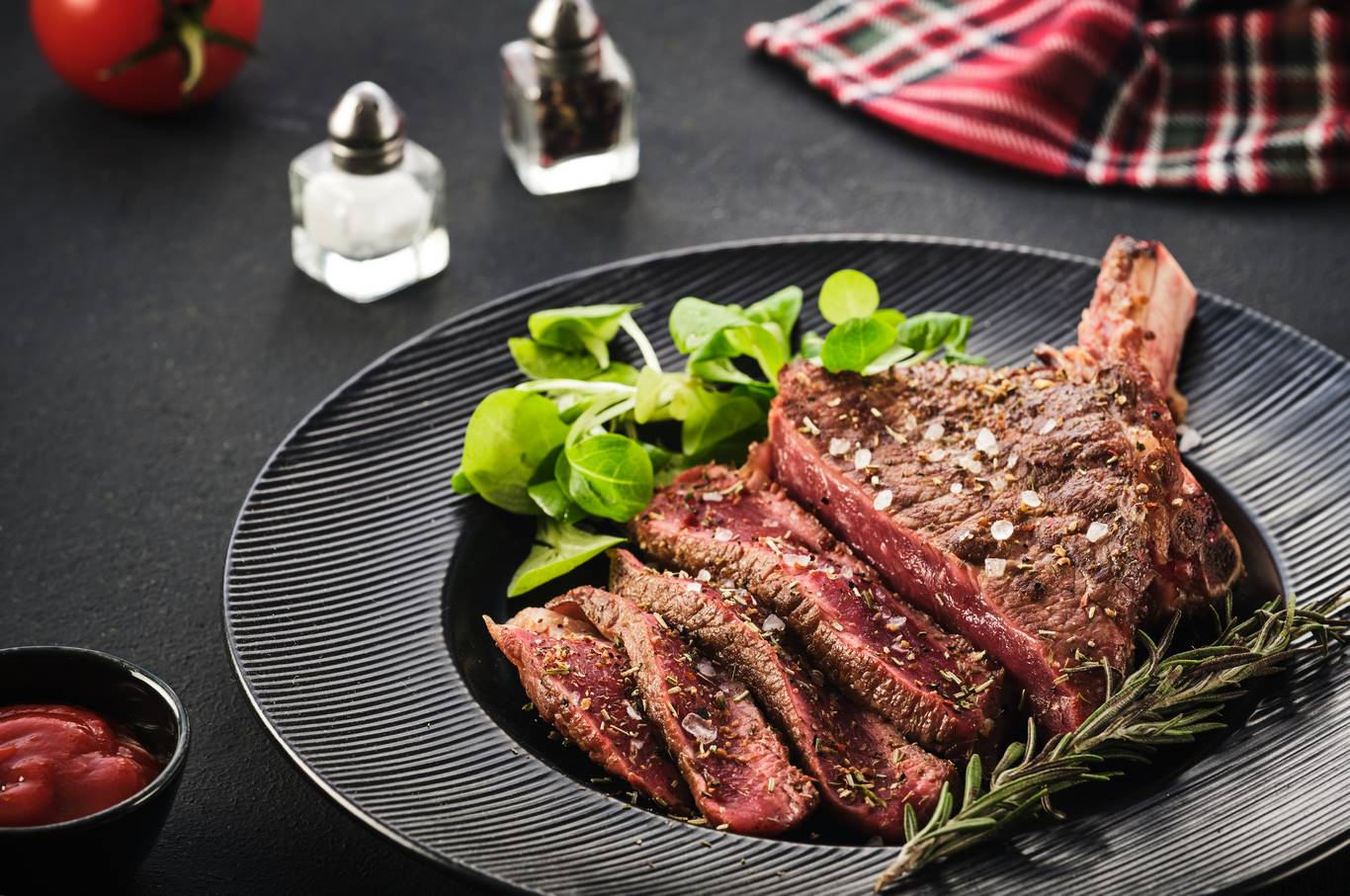 Steak on the bone. Rib eye. Tomahawk steak on the black plate wi